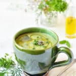 soupe froide de courgettes crues, citron, basilic, servie avec un filet d'huile d'olive et herbes fraîches
