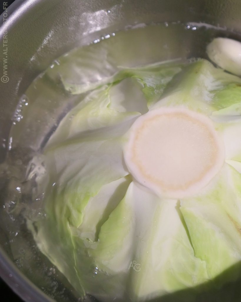 Demi-chou blanc plongé dans une casserole d’eau pour la précuisson